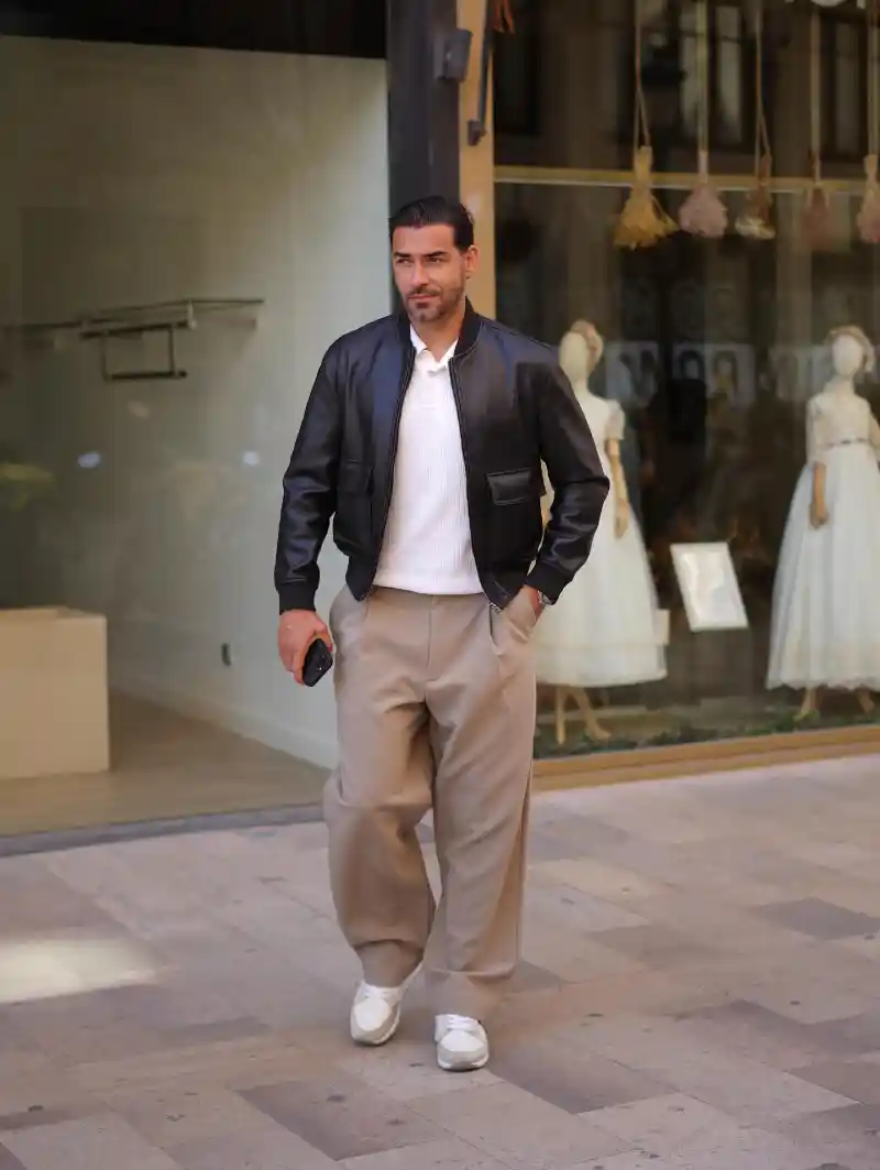 Black Leather Bomber Jacket, White Polo Shirt, and Beige Trousers