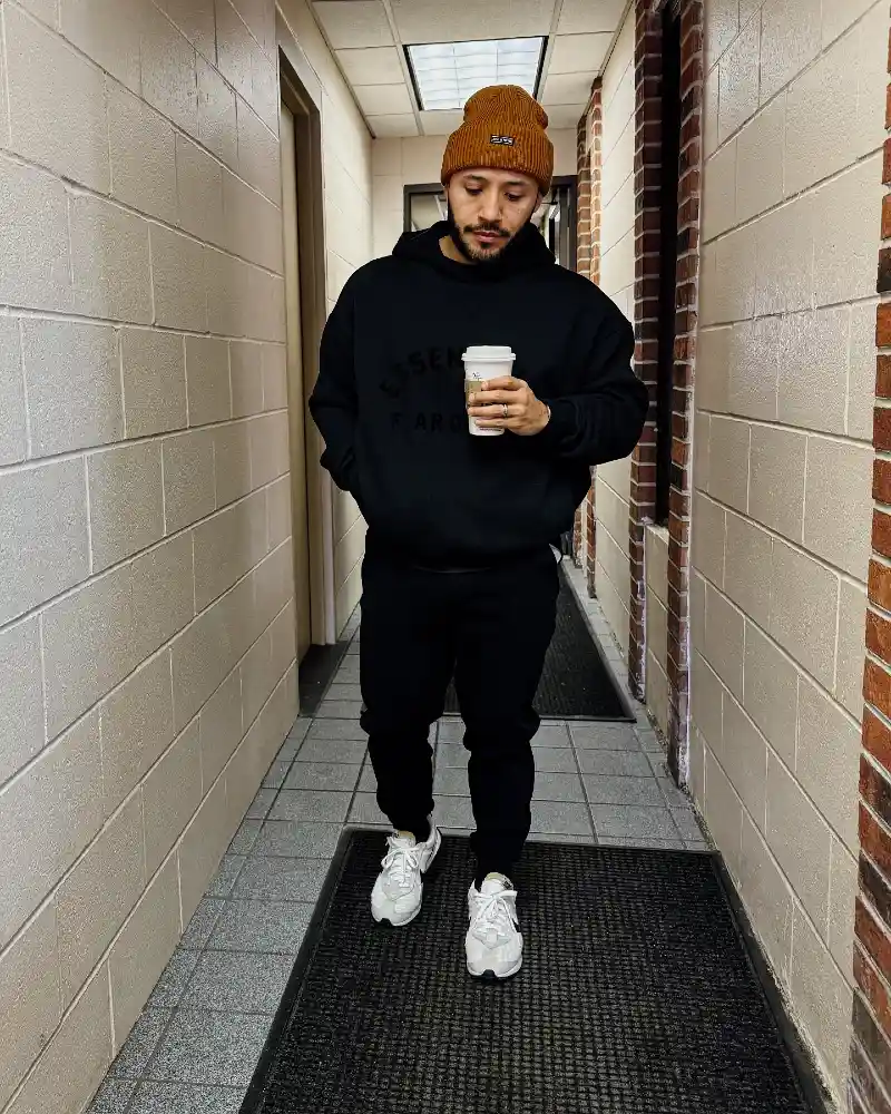 black hoodie, black joggers, white sneakers, and a tan beanie