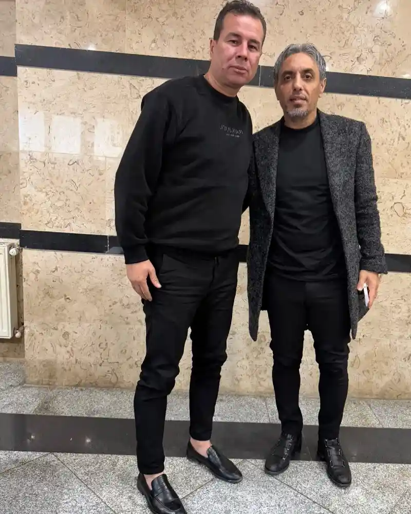 black sweatshirt, charcoal overcoat, black t-shirt, black trousers, and leather loafers