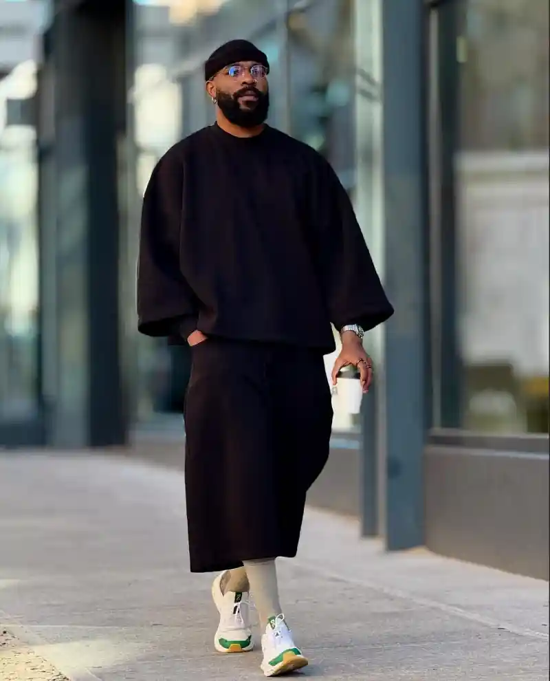 oversized black sweatshirt, black knee-length shorts, light grey socks, and white sneakers